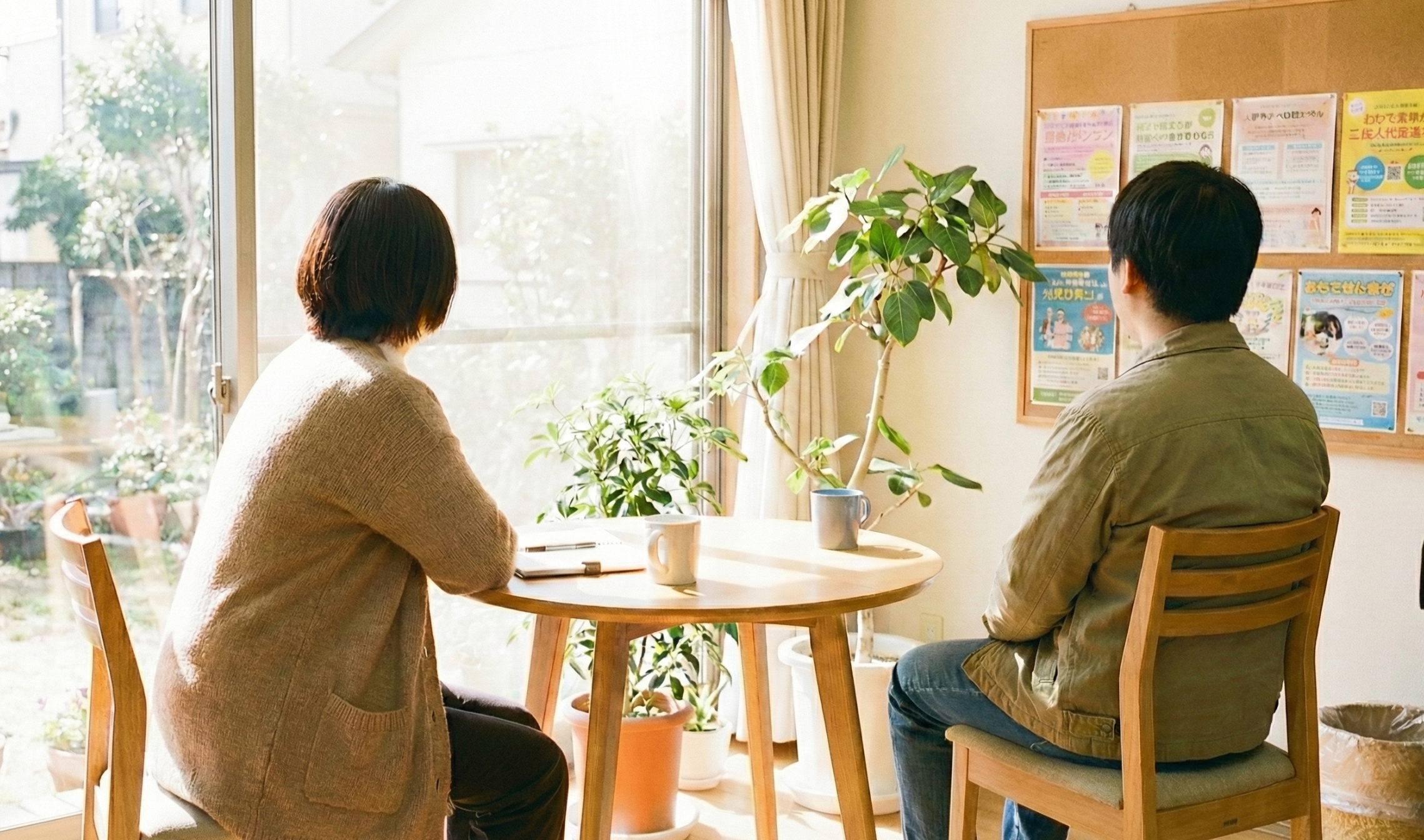 窓辺のテーブルで相談員と相談者がリラックスした雰囲気で腰掛けているイメージ